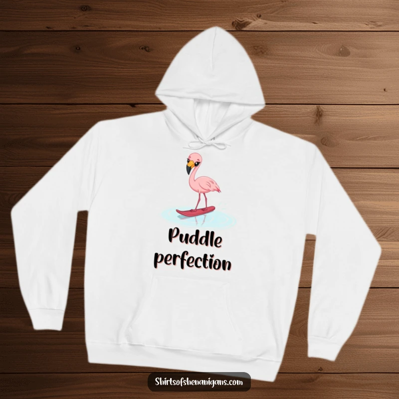 Funny startled flamingo hoodie, cross-eyed and water skiing on a puddle, offering cozy and comical style.