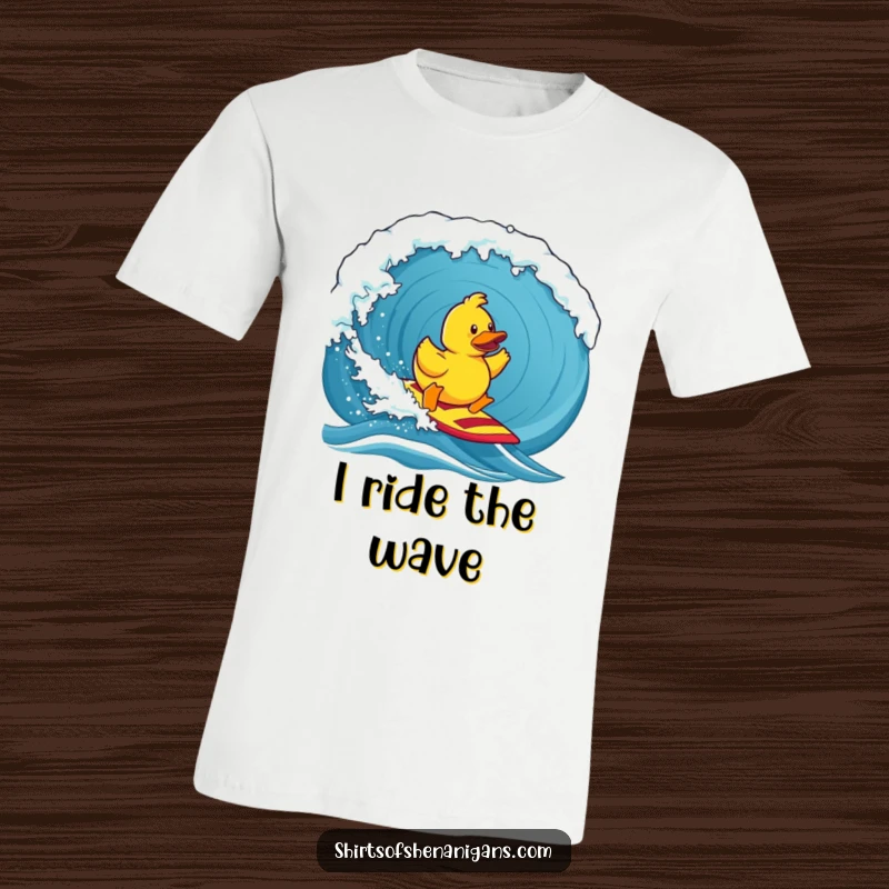 Funny t-shirt, a determined rubber duck bravely surfing a huge ocean wave, conveying playful courage and aquatic adventure.